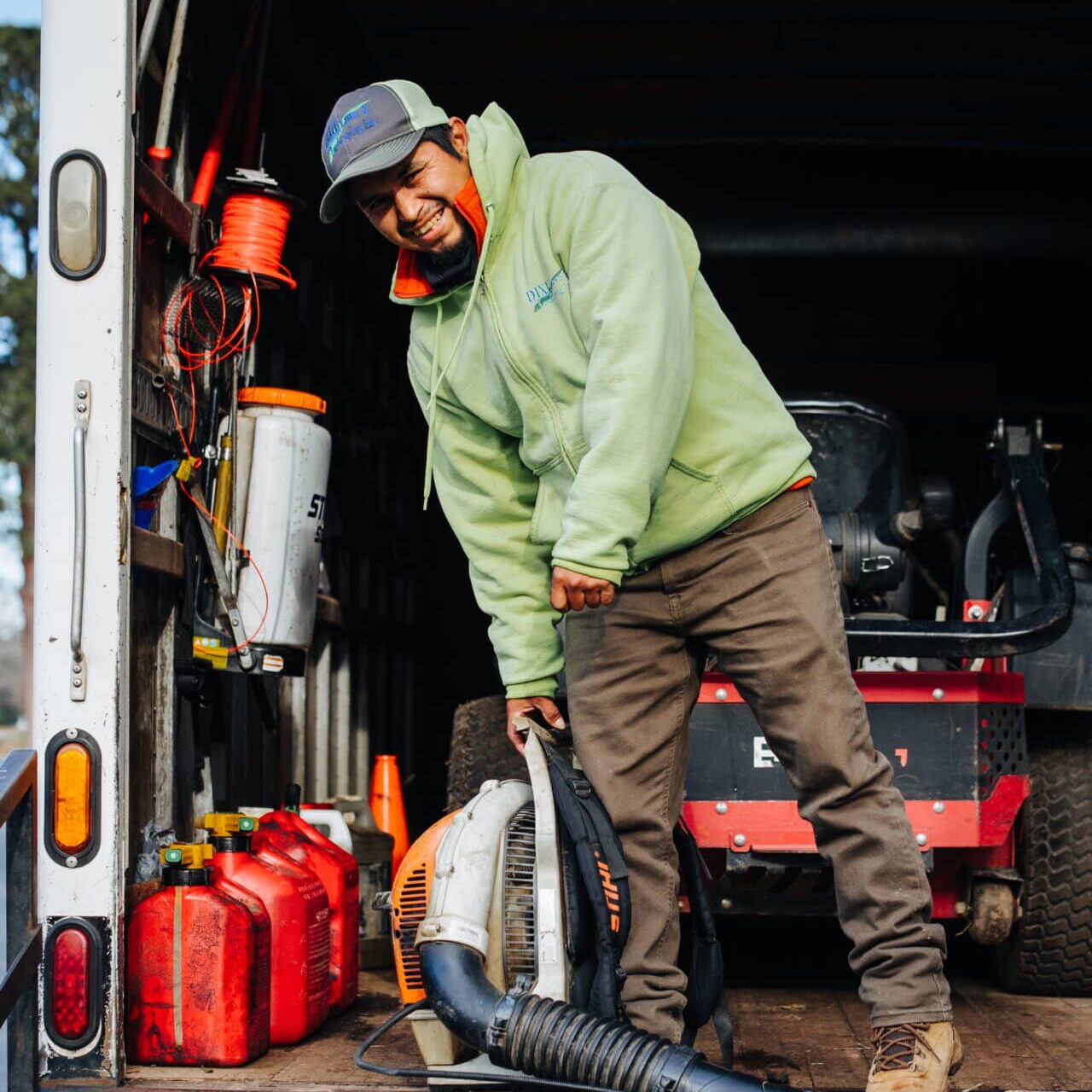 worker in the back of a company work truck smiling at the camera