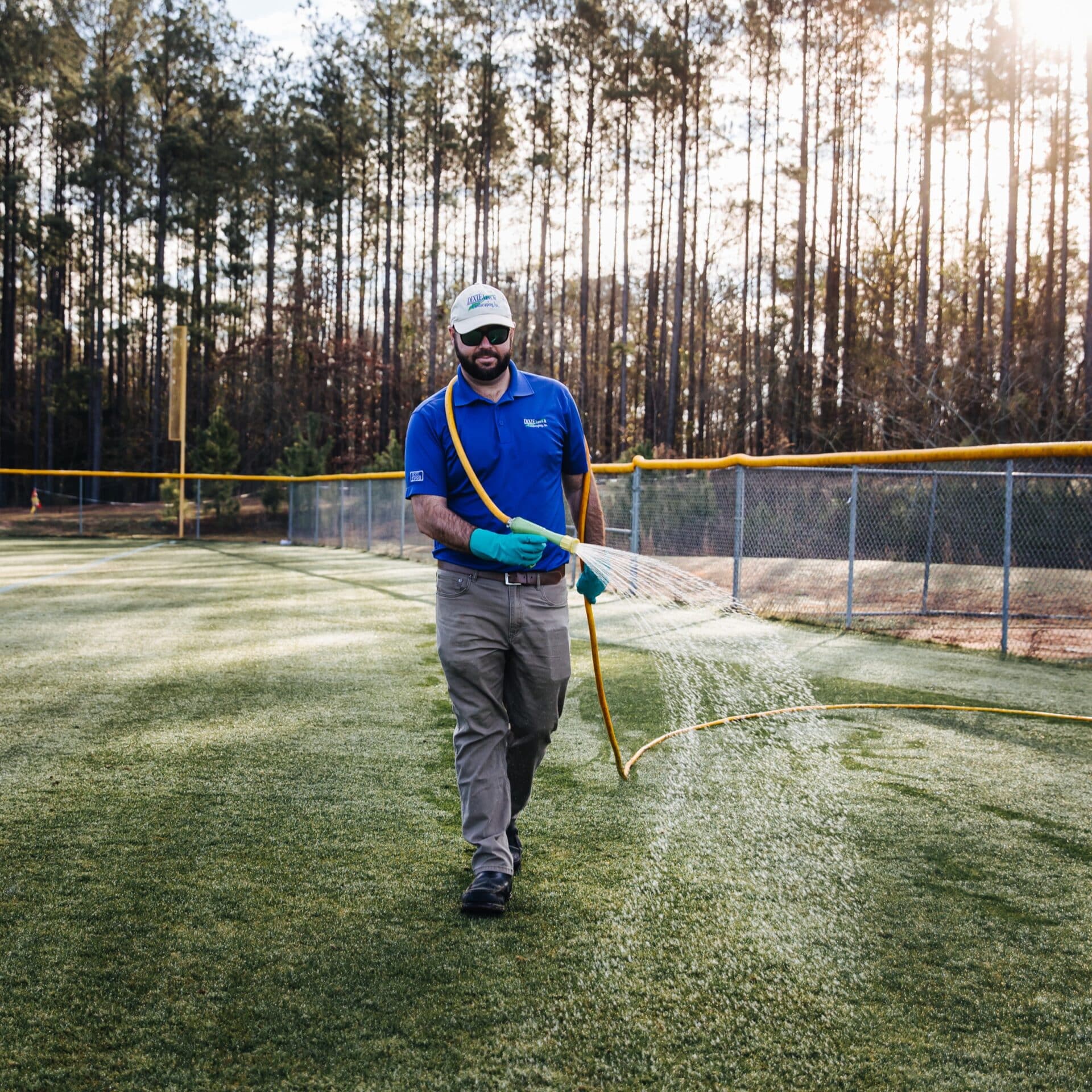 man spraying a hose onto an athletic field