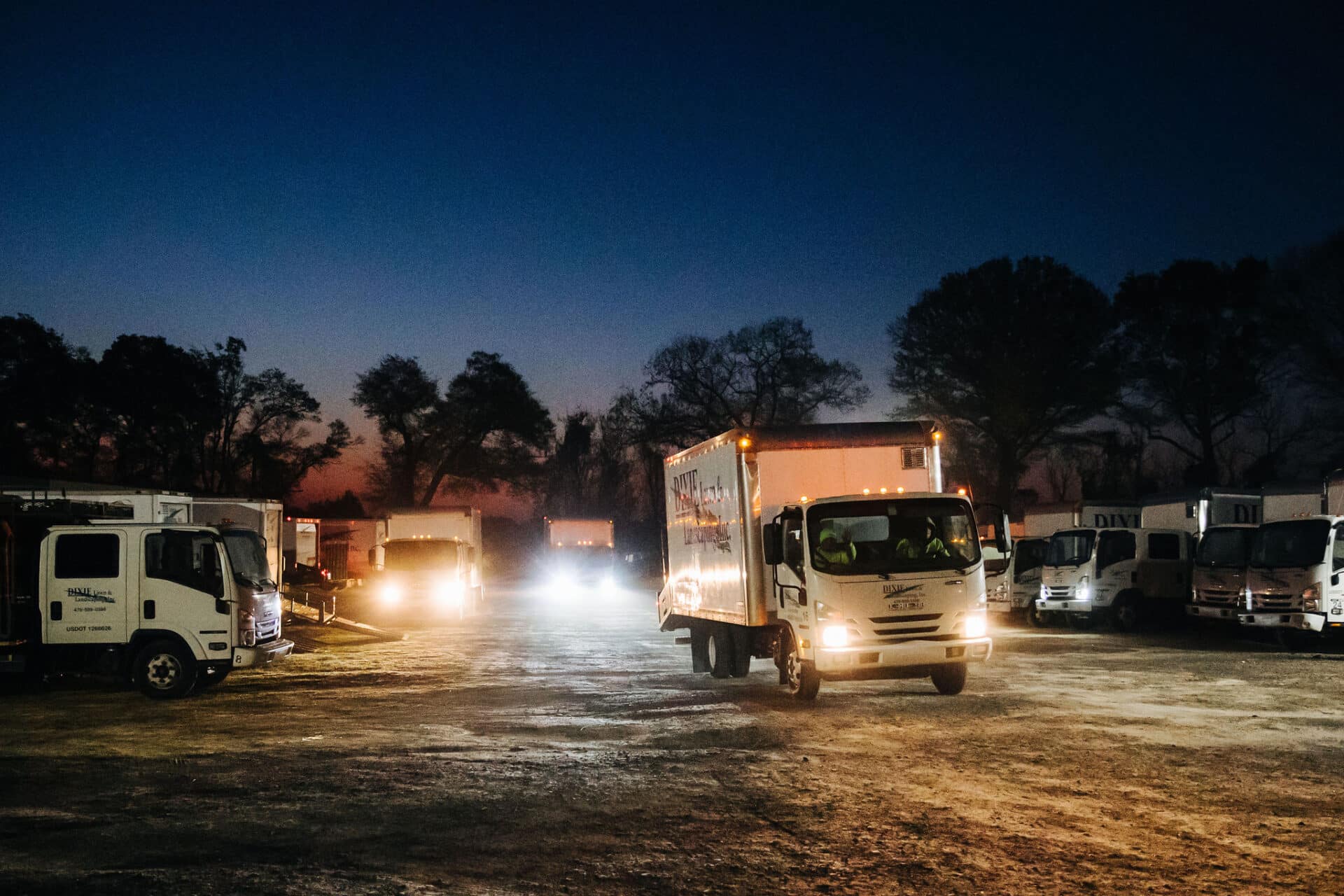 nighttime image of field with work trucks ready to drive off